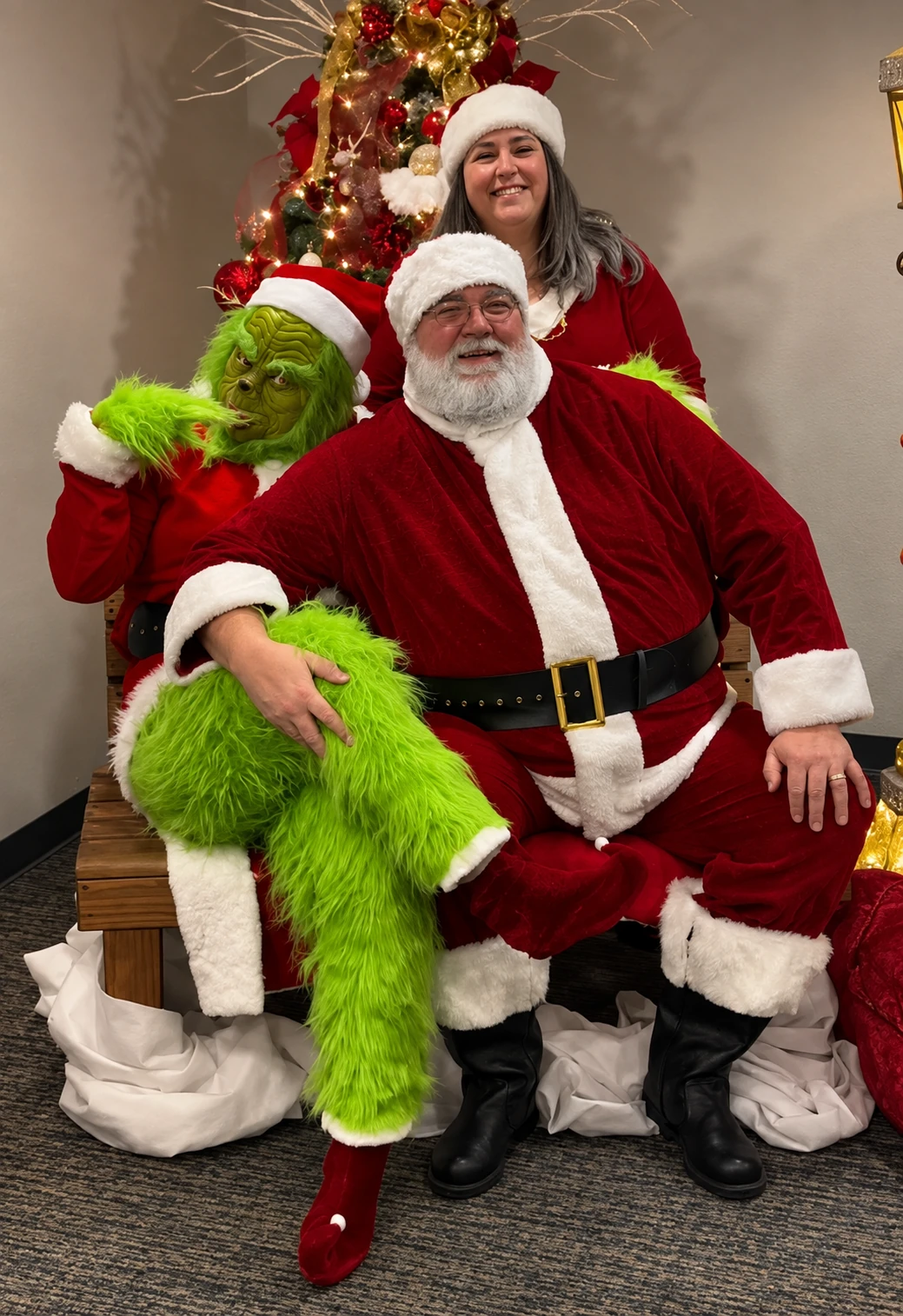 Santa Jeff, the Grinch, and a woman in a Santa hat smiling together